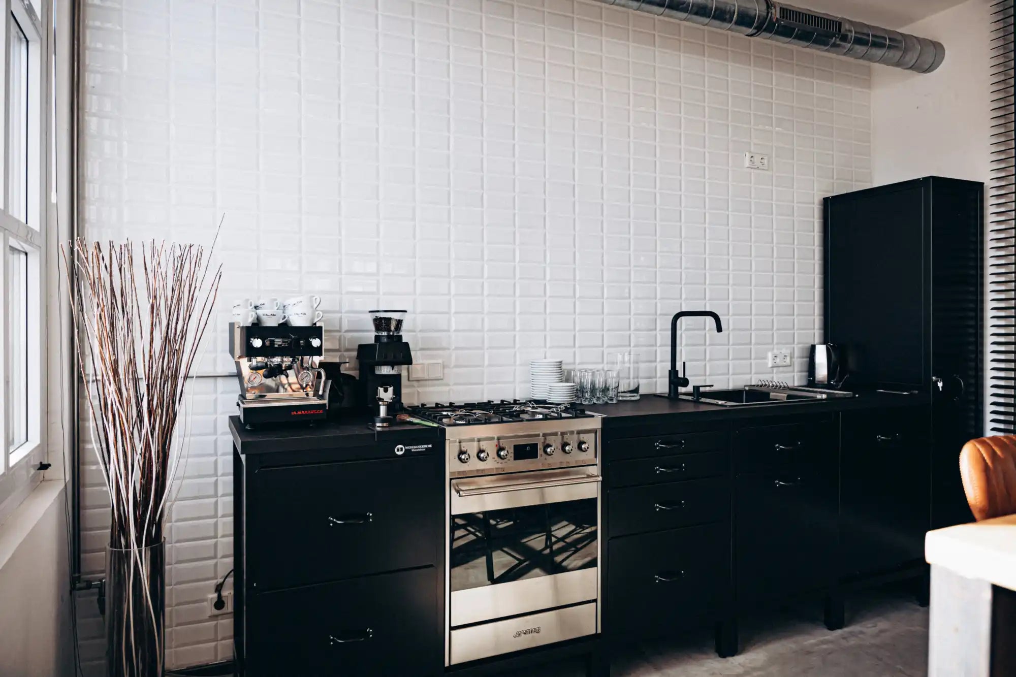 Black matte kitchen cabinet with silver hardware and glass door panels.